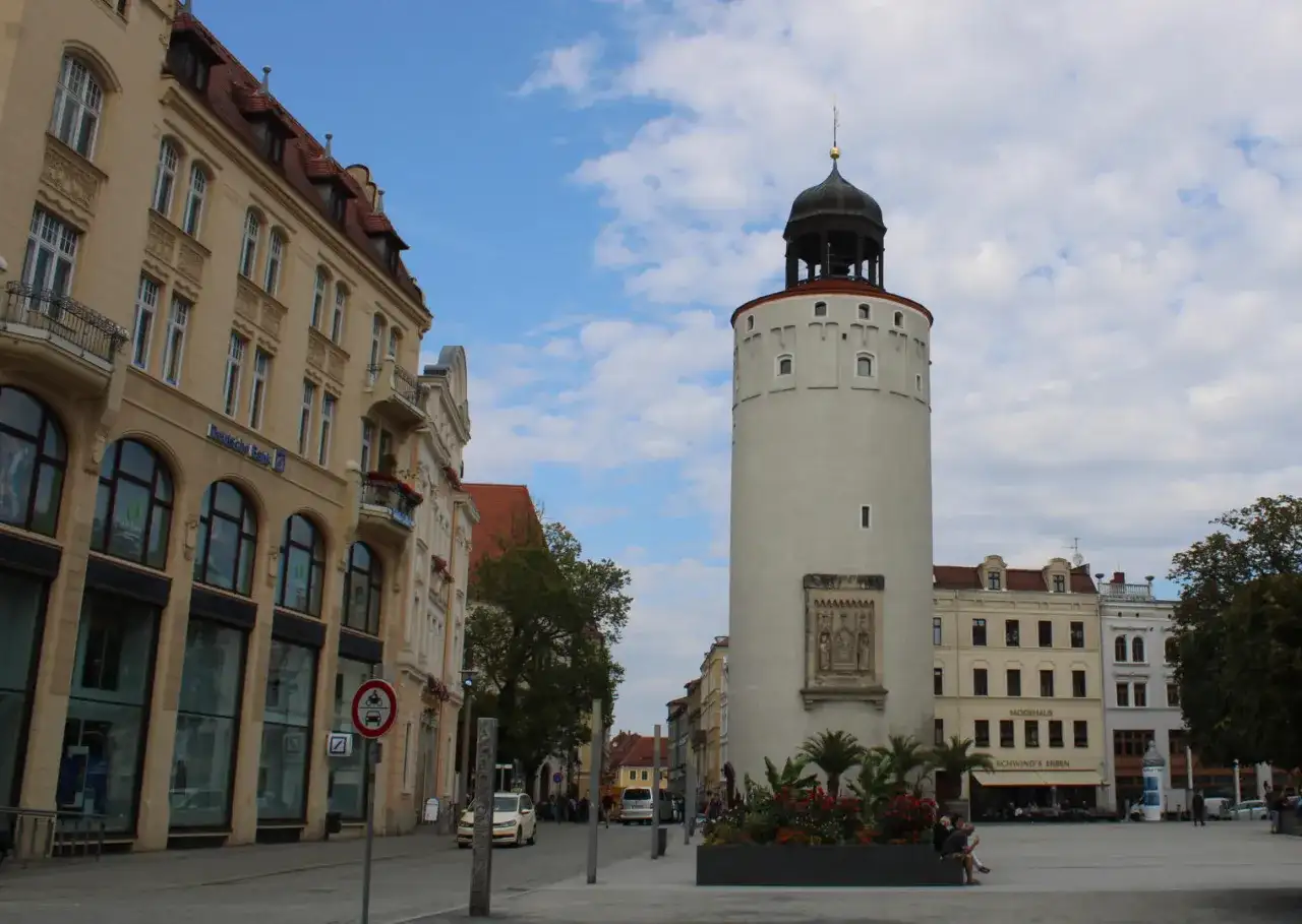 Der Reichenturm dominiert den Marienplatz Görlitz, flankiert von historischen Gebäuden und blühenden Blumenbeeten.