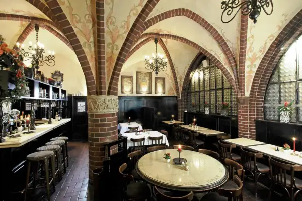 Gemütliche Atmosphäre in einem Berliner Restaurant mit Gewölbedecke, Kronleuchtern und Holztischen.