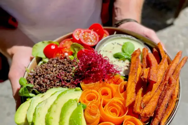 Ein farbenfroher Buddha Bowl mit Quinoa, Avocado, Karottenrosen, Süßkartoffel-Pommes und einem cremigen Dip. So schmeckt froindlichst Berlin!